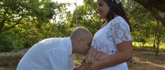 future father kisses his pregnant wife&#39;s belly